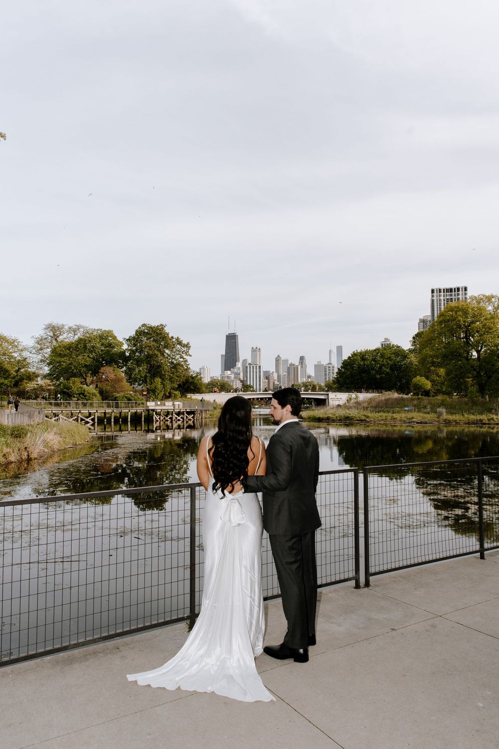 A series of wedding photos showing a couple in formal attire posing against metal railings with an urban waterfront backdrop.