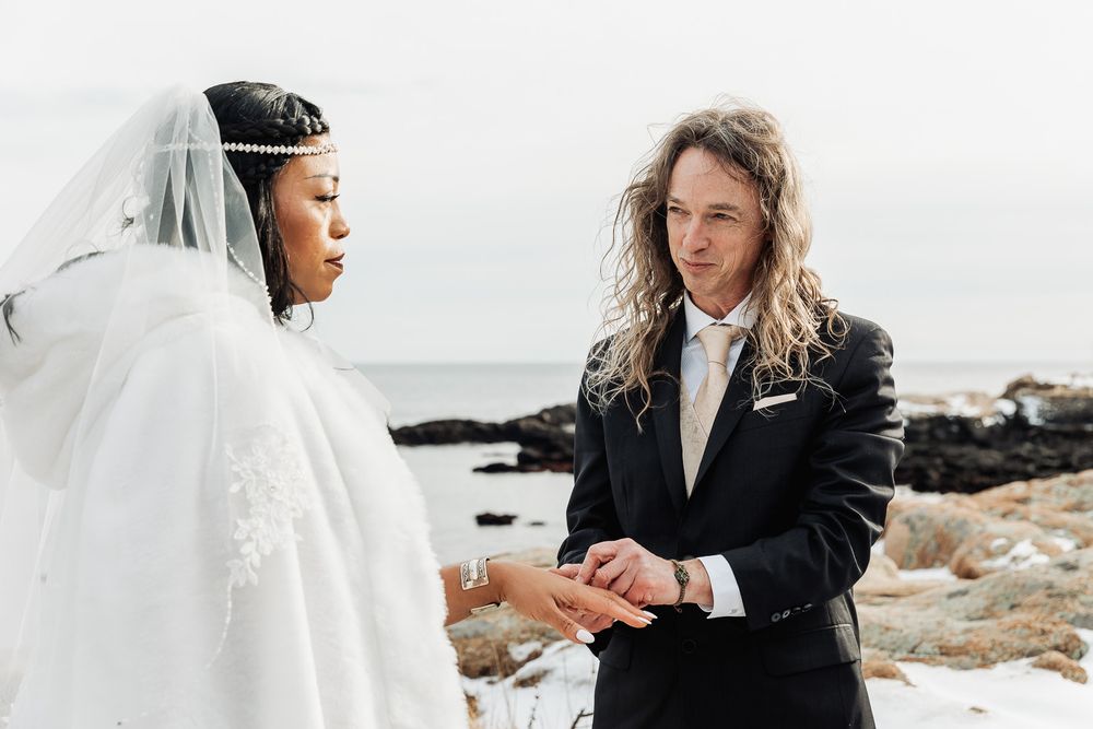 Couple sharing a romantic moment during their wedding ceremony against a scenic coastal backdrop.