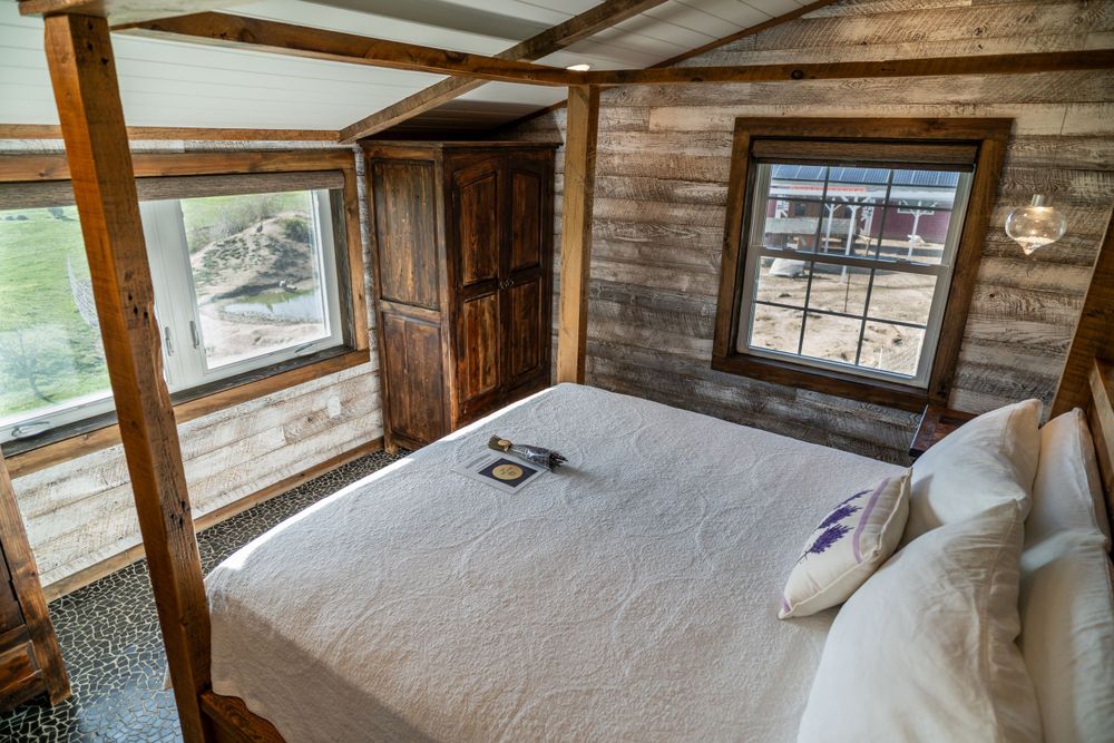 Bed with a lavender bundle and Airbnb welcome letter in a cozy wooden room, creating a warm, inviting atmosphere. Airbnb bedroom.