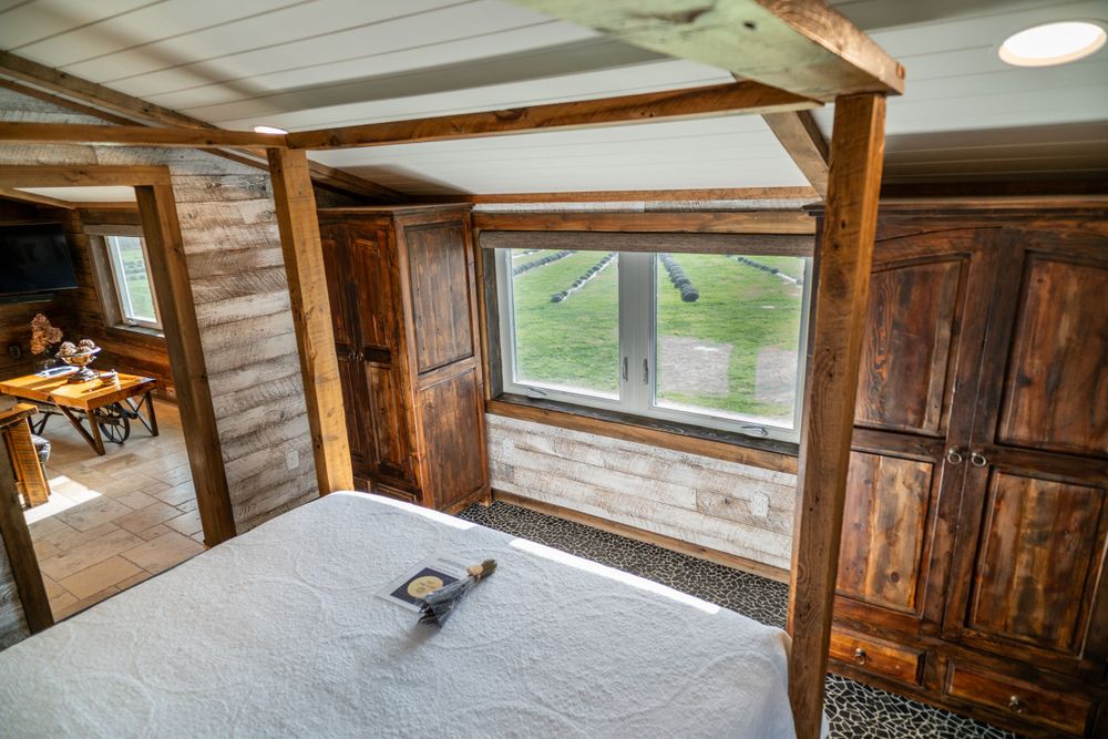 Bed with a lavender bundle and Airbnb welcome letter in a cozy wooden room, creating a warm, inviting atmosphere. Airbnb bedroom.