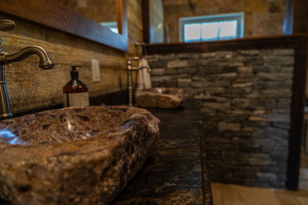 Close-up of a natural amethyst stone sink, showcasing its unique texture and elegant design in a unique bathroom. Rock wall in background