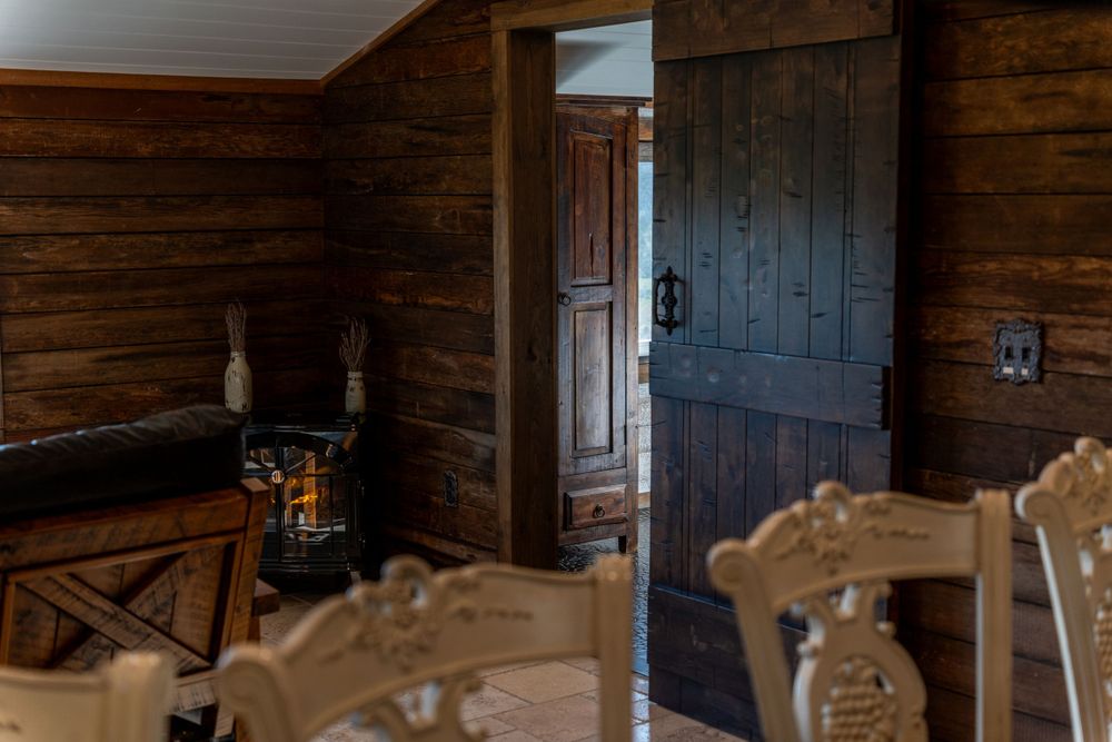 Doorway view in a beautiful wooden house featuring an electric fireplace, cozy couch, and counter chairs in an inviting space.