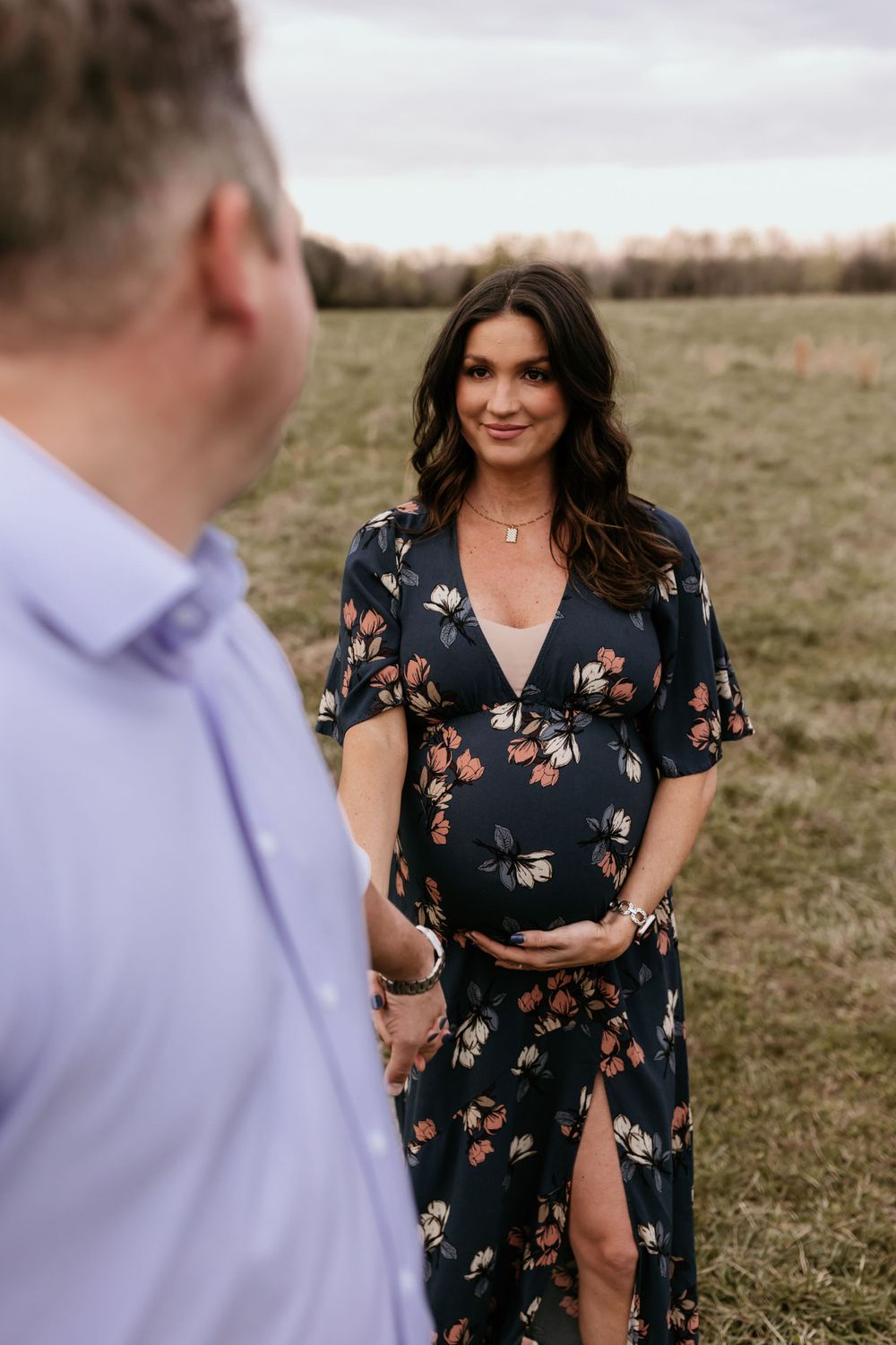 A floral maternity dress photo session in an open field during golden hour.