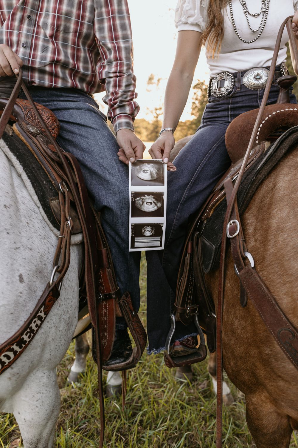 Two people on horseback sharing ultrasound photos between their saddles.