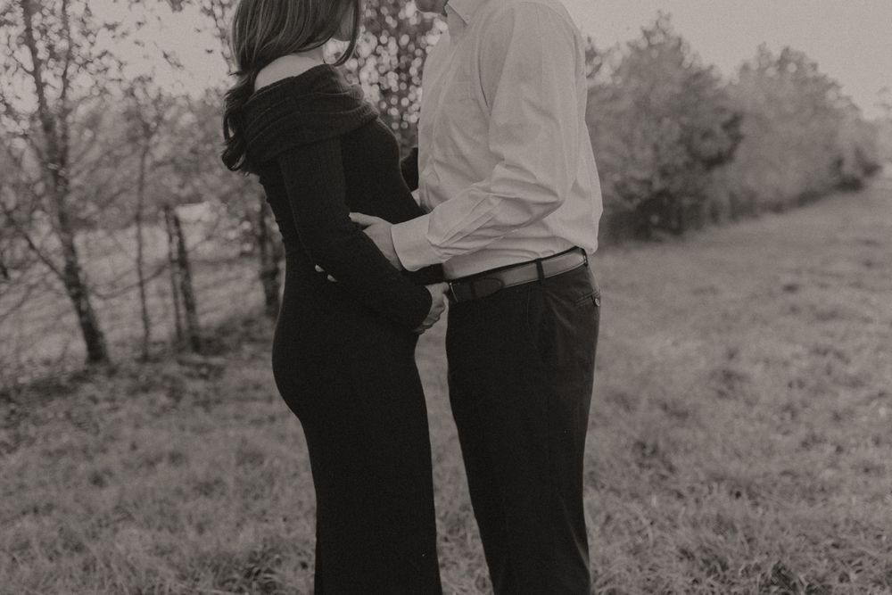Black and white maternity photo showing couple's silhouette in a field.