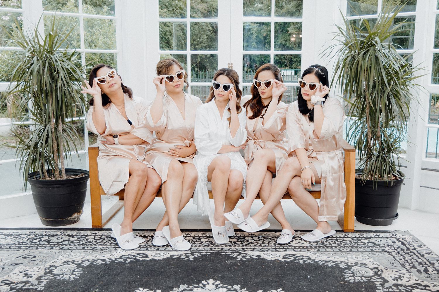 Five people in matching blush robes and sunglasses captured by Apertured Media Auckland Wedding Photographer.
