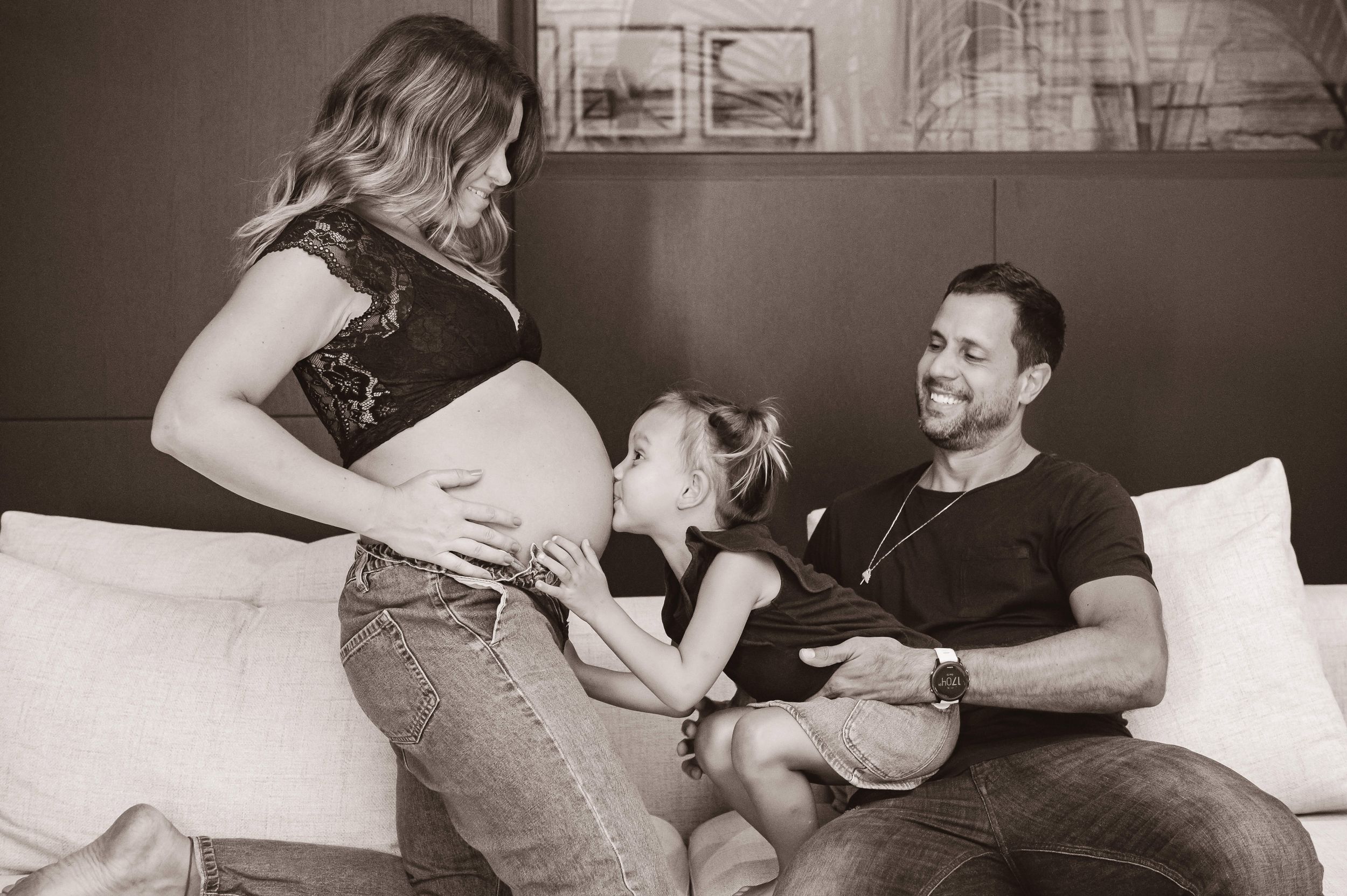 A tender black and white family moment captured on a couch during a maternity photography session.