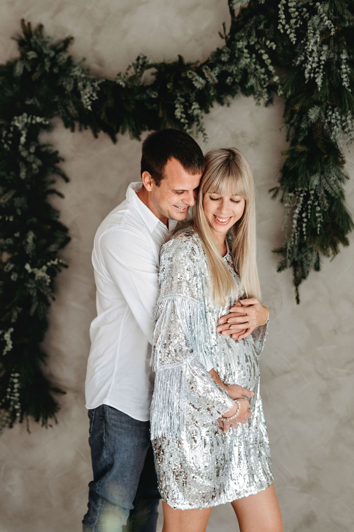 A romantic moment captured against a wall adorned with evergreen garland and moody lighting.