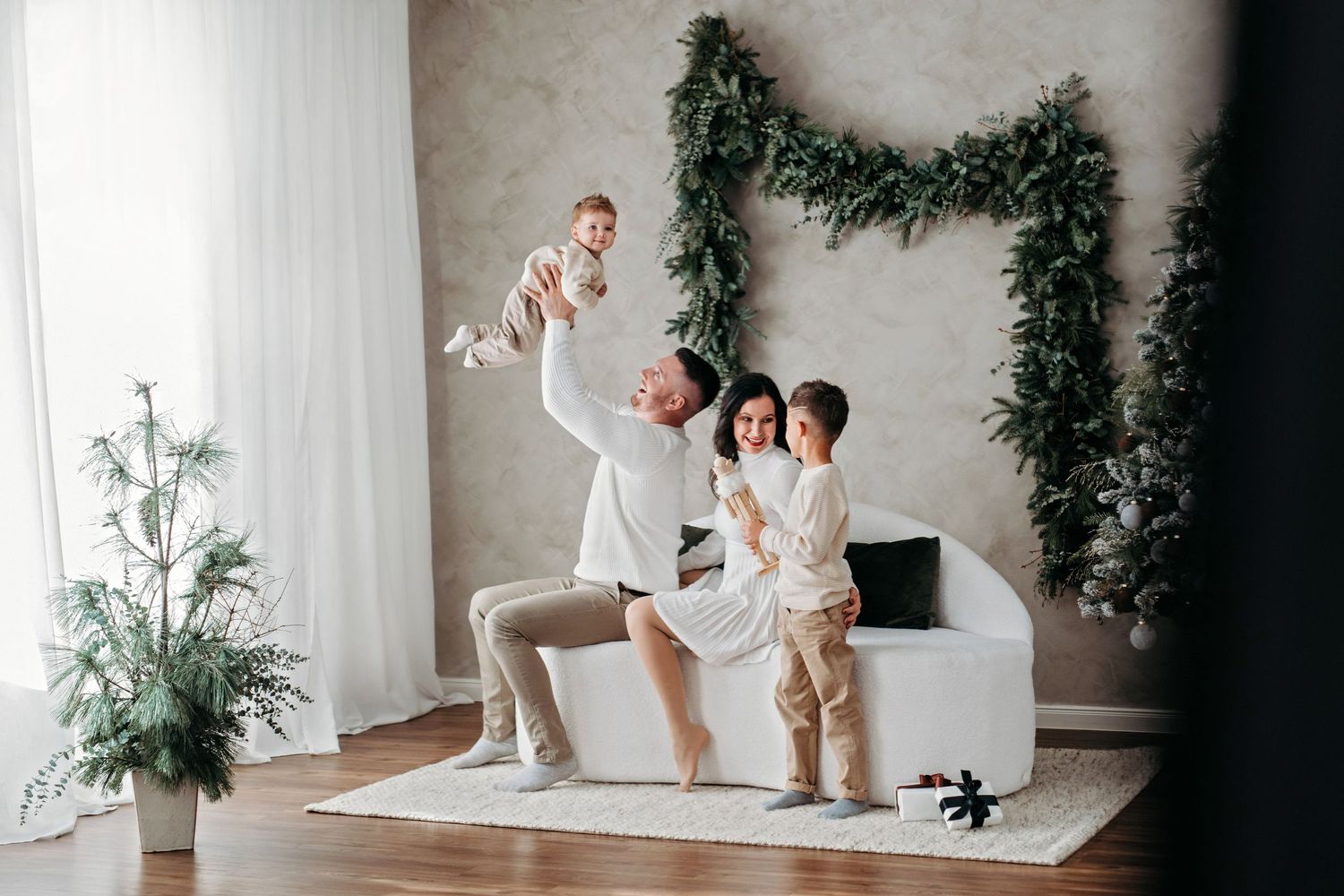 A playful indoor family scene with evergreen garland decor and joyful interactions.