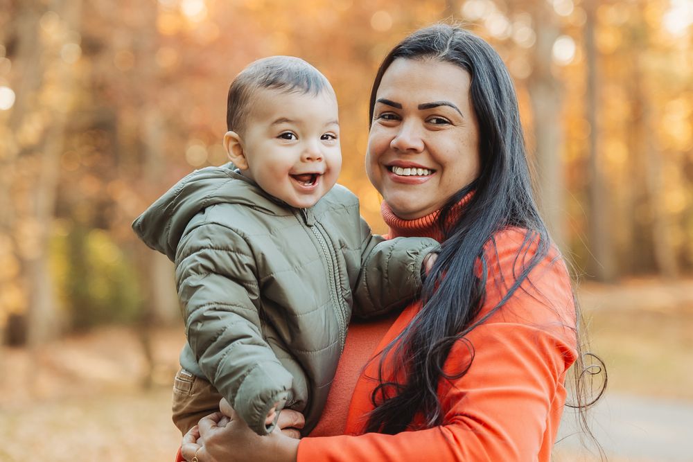 A heartwarming autumn scene with a young child and caregiver enjoying the outdoors together.