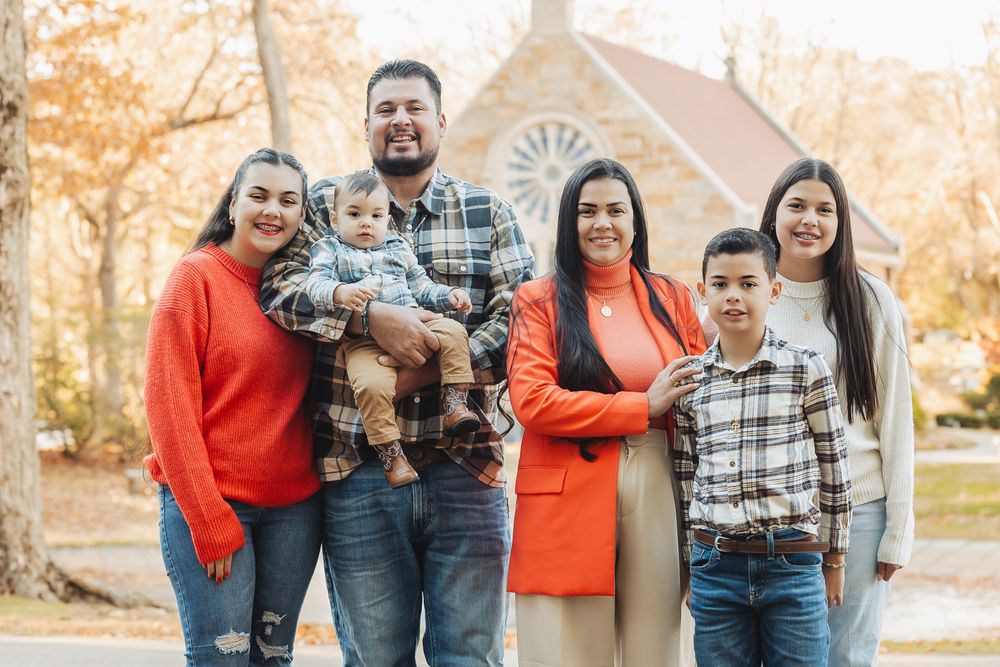 Family gathering outdoors with historic church building visible in background.