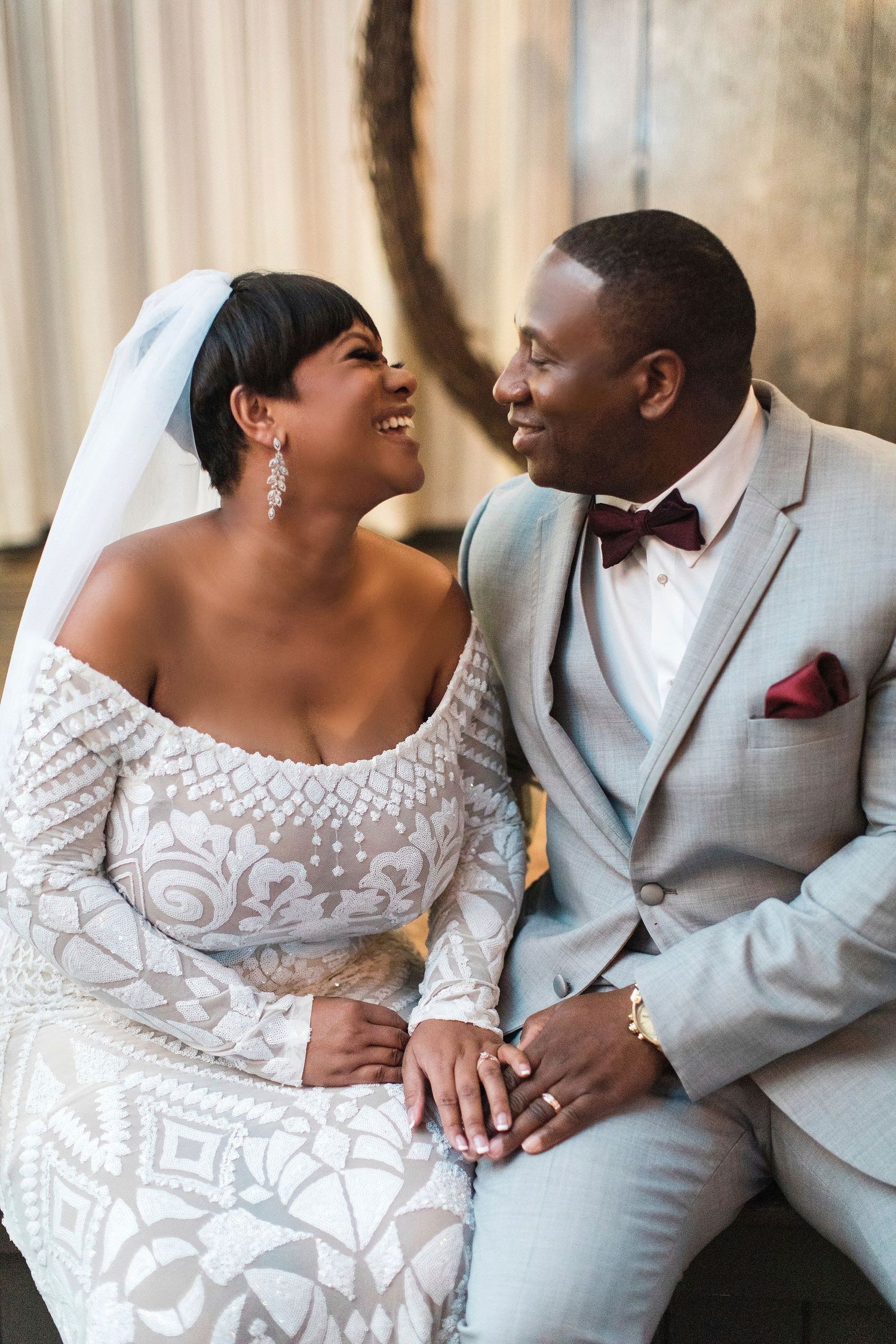 Newlyweds in elegant attire share a joyful moment during their wedding celebration.