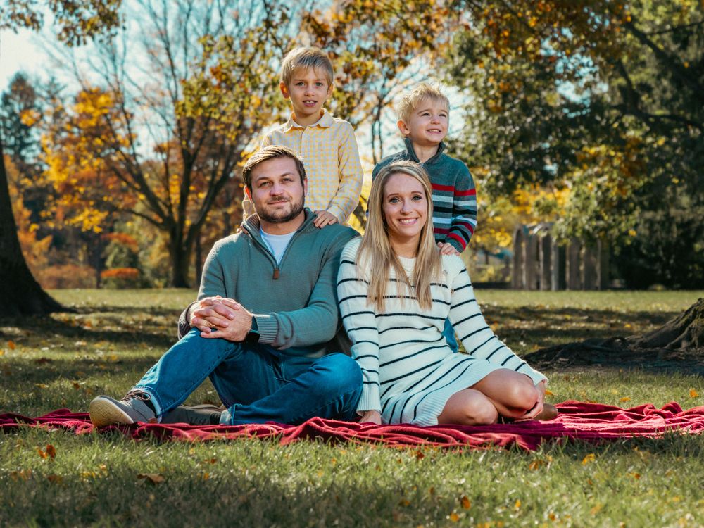 Family relaxing on a red blanket during an autumn photo session.