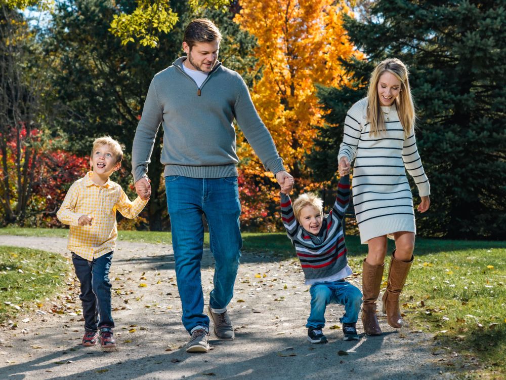 Family walking hand in hand down a path with vibrant fall foliage.