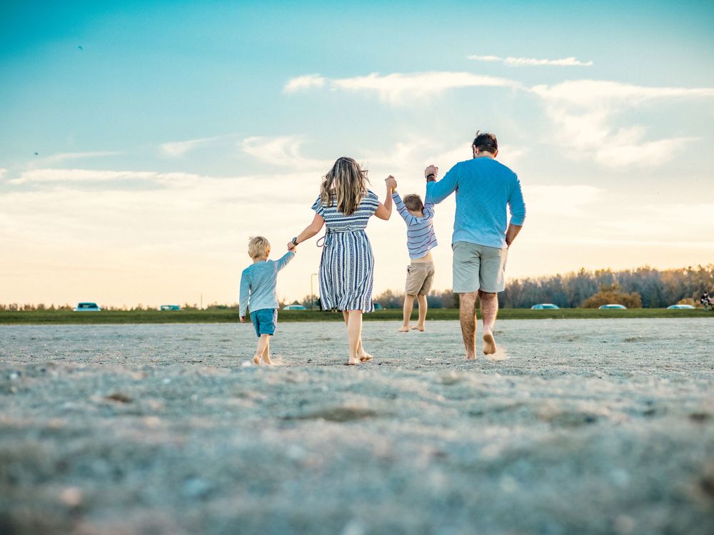 Family runs together on beach holding hands during golden hour.