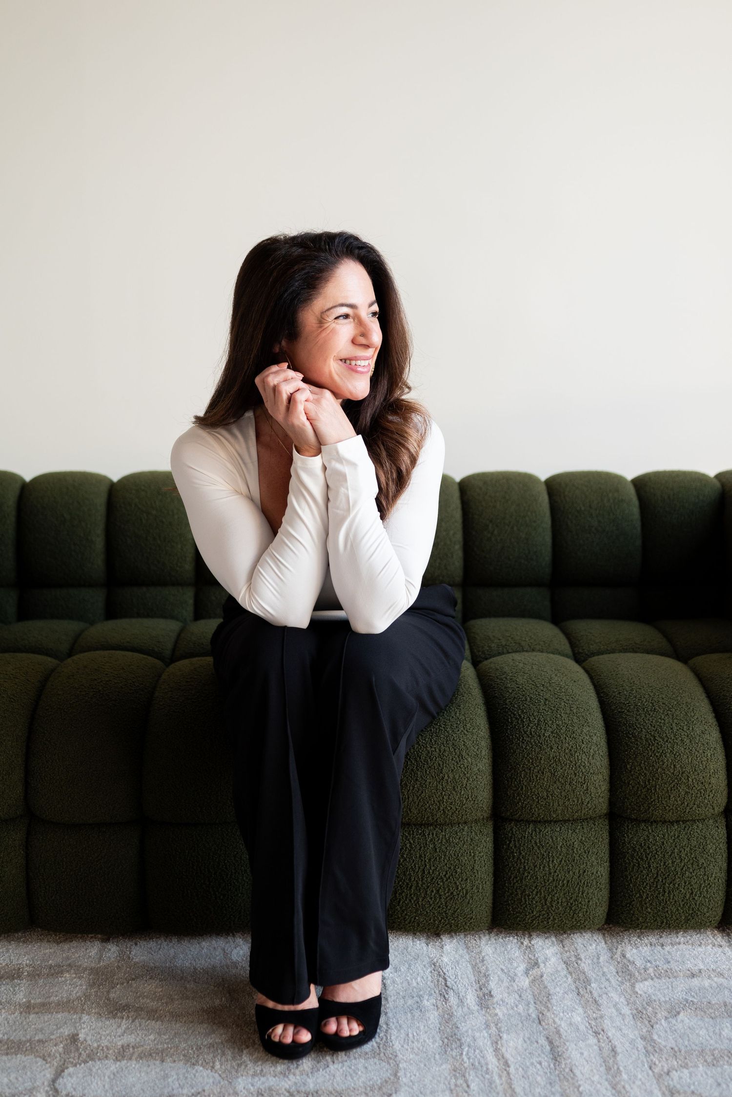 A relaxed portrait on a plush green sectional sofa wearing business casual attire.