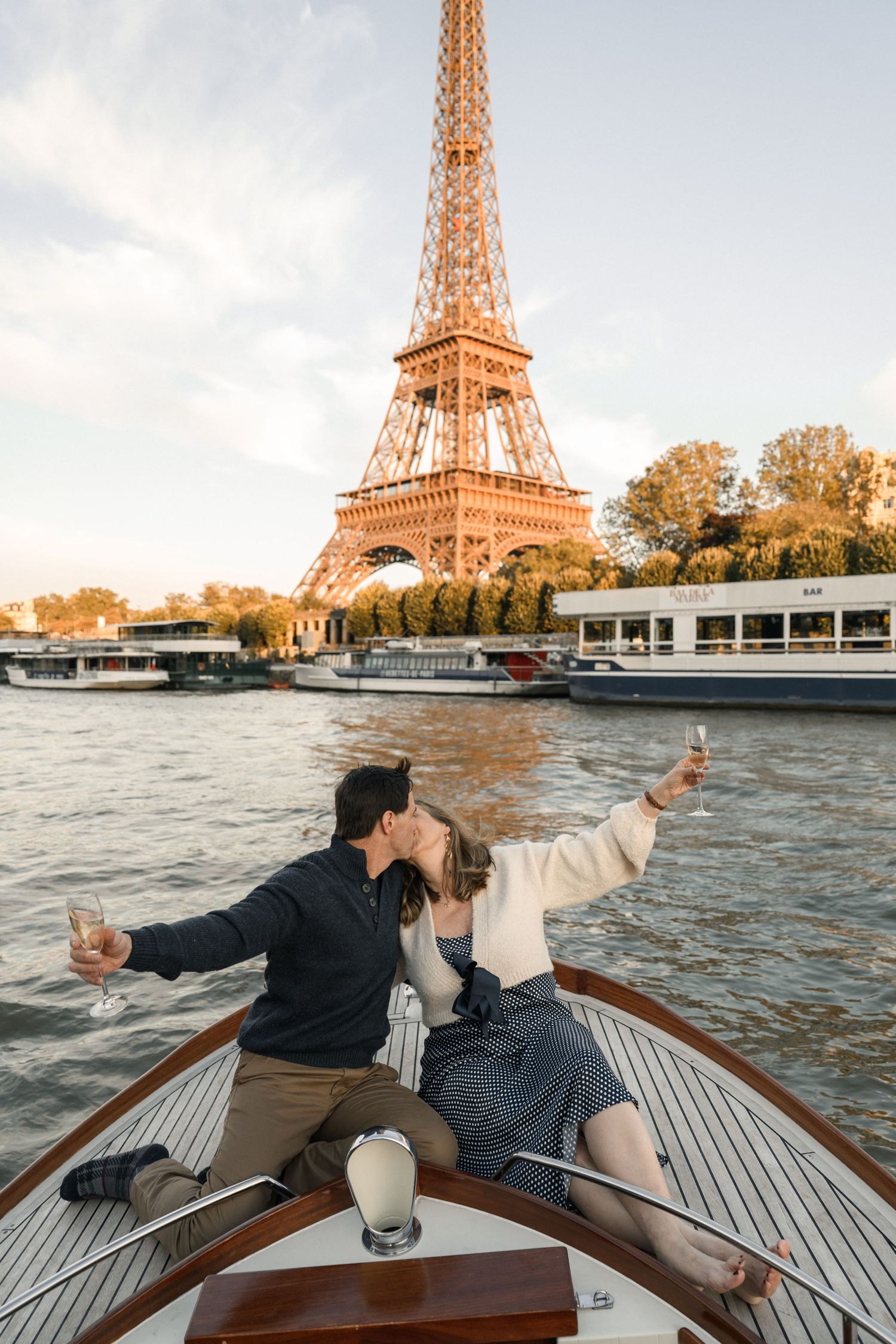 A romantic black and white embrace of a couple at a scenic overlook with cityscape and water views in the background.