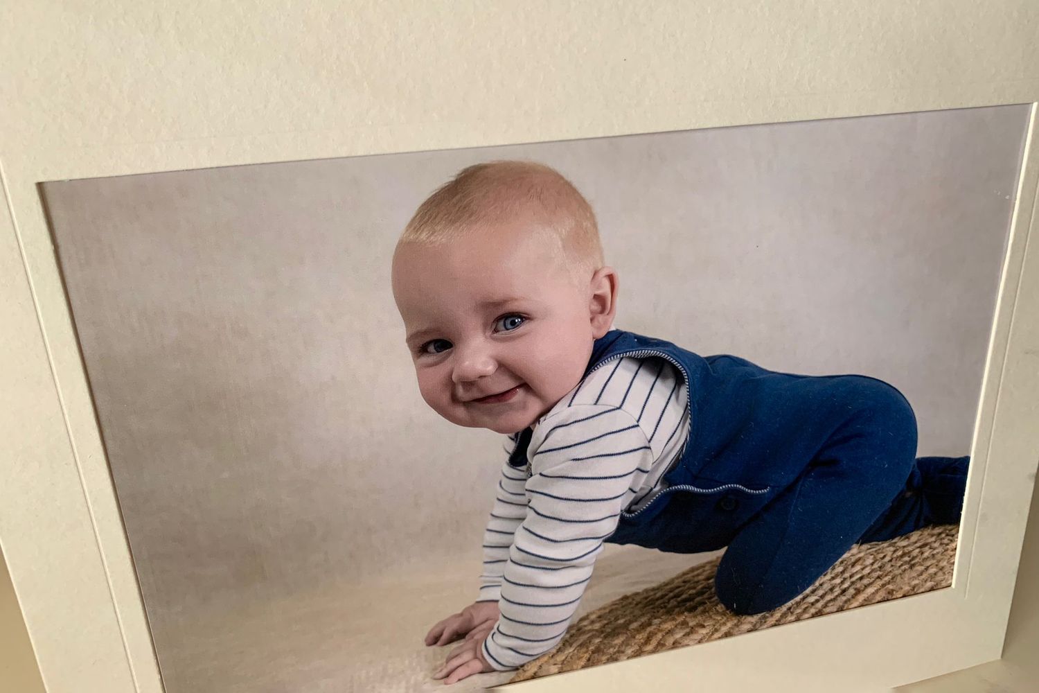 A crawling baby in a striped shirt moves along a repeating series of wooden cubby shelf spaces.