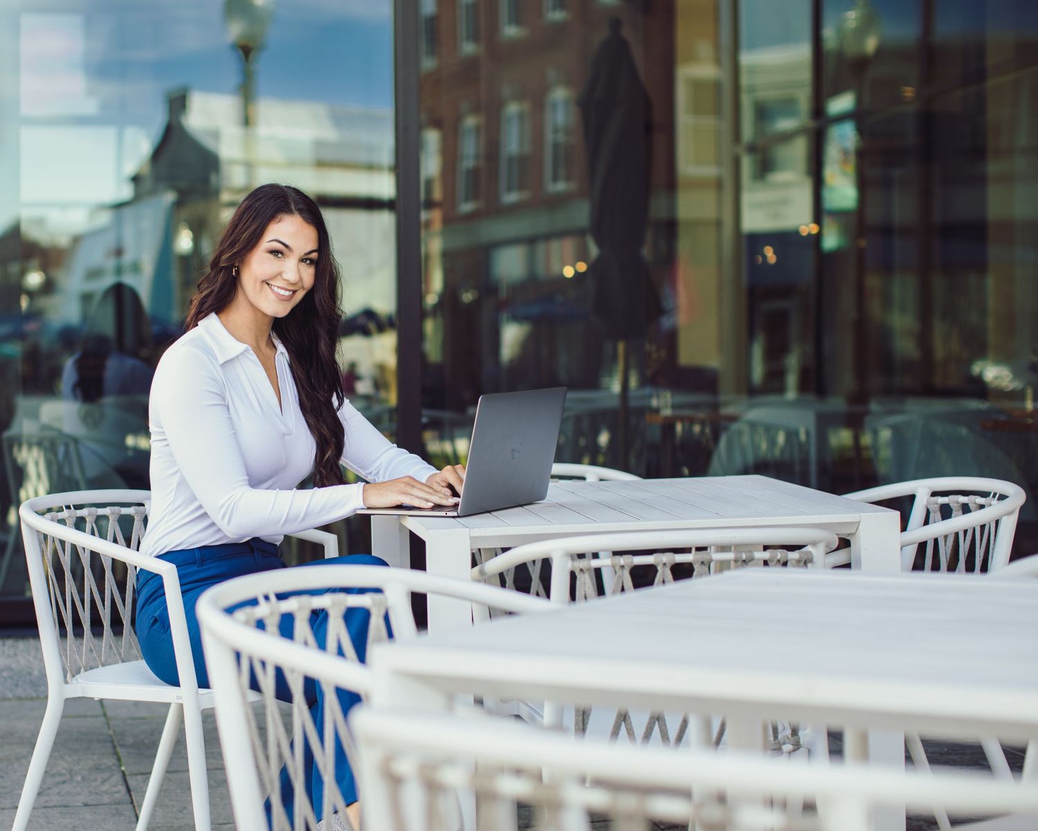 A professional photo of a woman sitting at a table with a laptop
