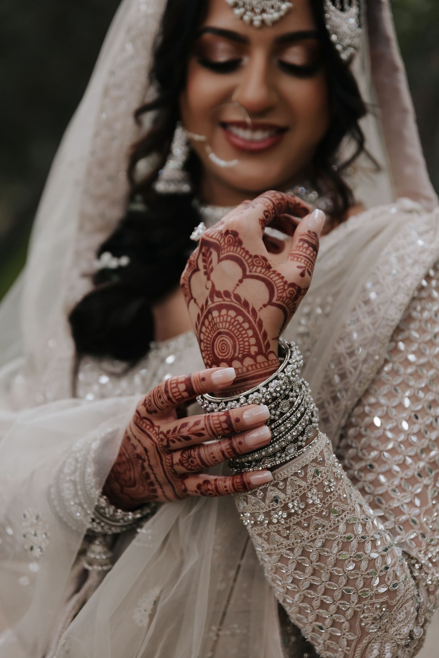 Detailed view of traditional henna designs and bangle bracelets with sparkly wedding attire.