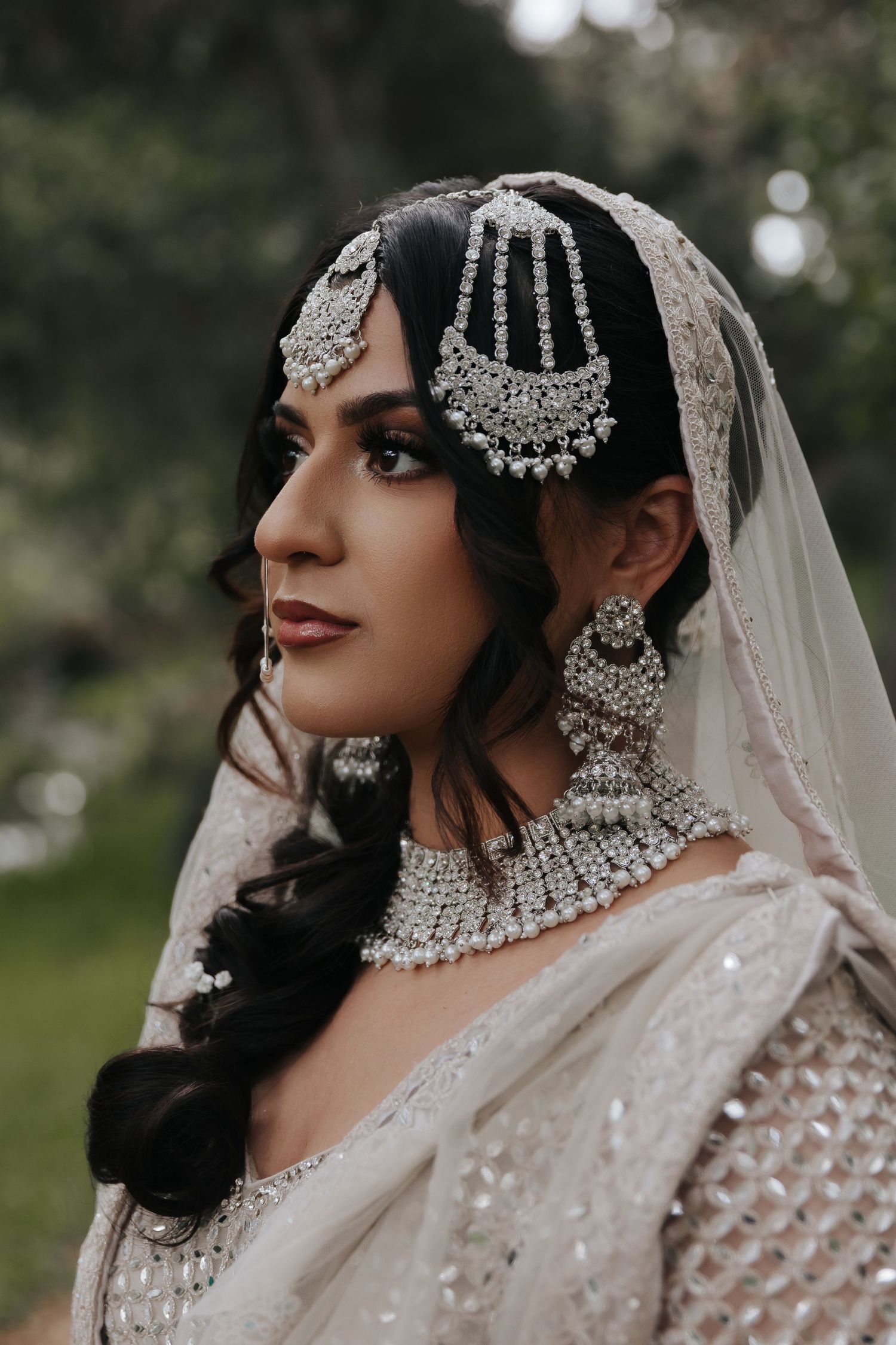Detailed shot of bridal jewelry and traditional South Asian wedding attire featuring intricate silver accessories.