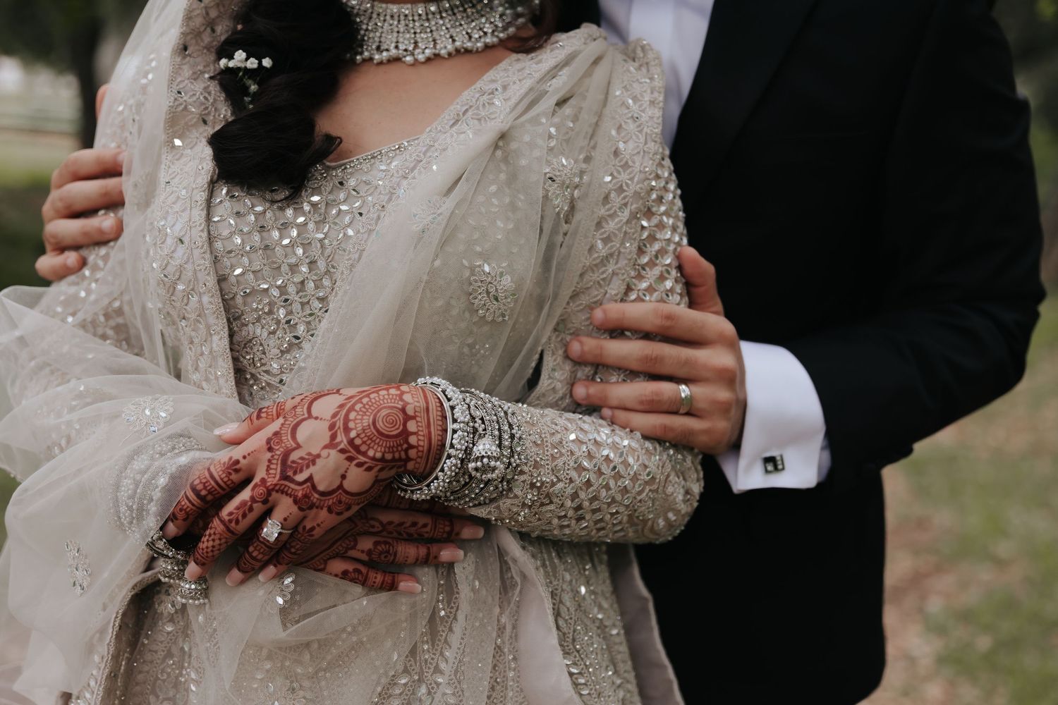 Close-up shots of silver bangles and mehndi adorned hands against white embellished fabric.