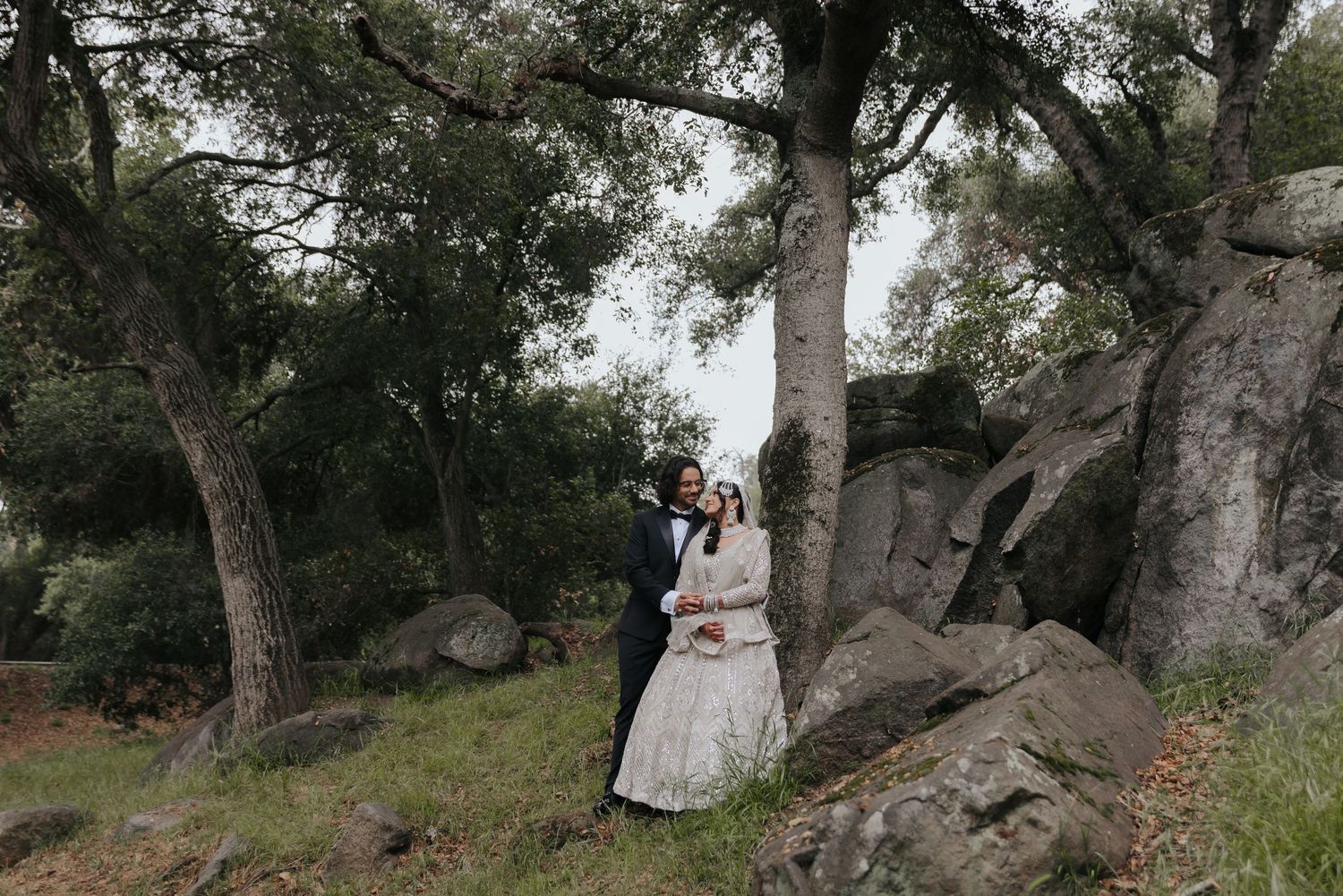 Natural wooded outdoor setting with rustic trees creating romantic backdrop for wedding photography.