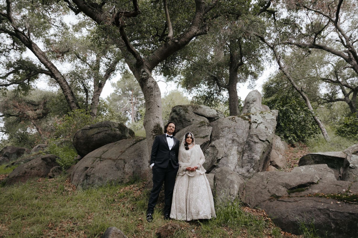 Romantic wedding photography sequence among rustic trees and rocks in a natural outdoor setting.