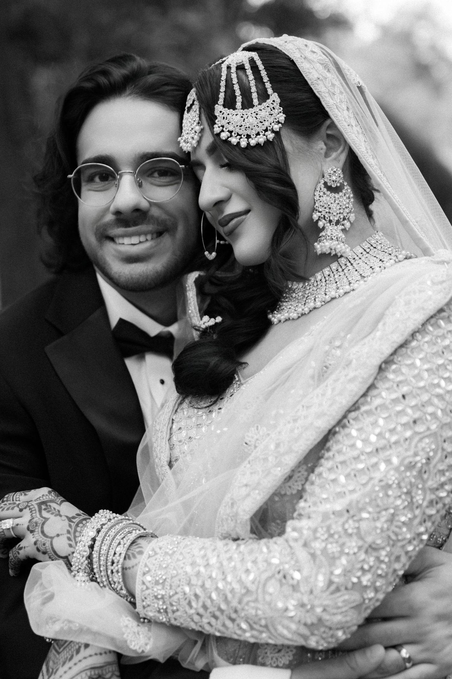 A tender black and white portrait of newlyweds with the bride wearing traditional South Asian bridal jewelry.