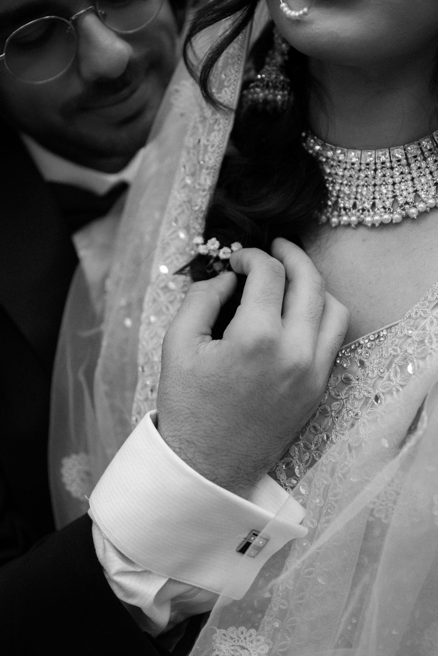 Black and white close-up of diamond necklace and formal attire details.