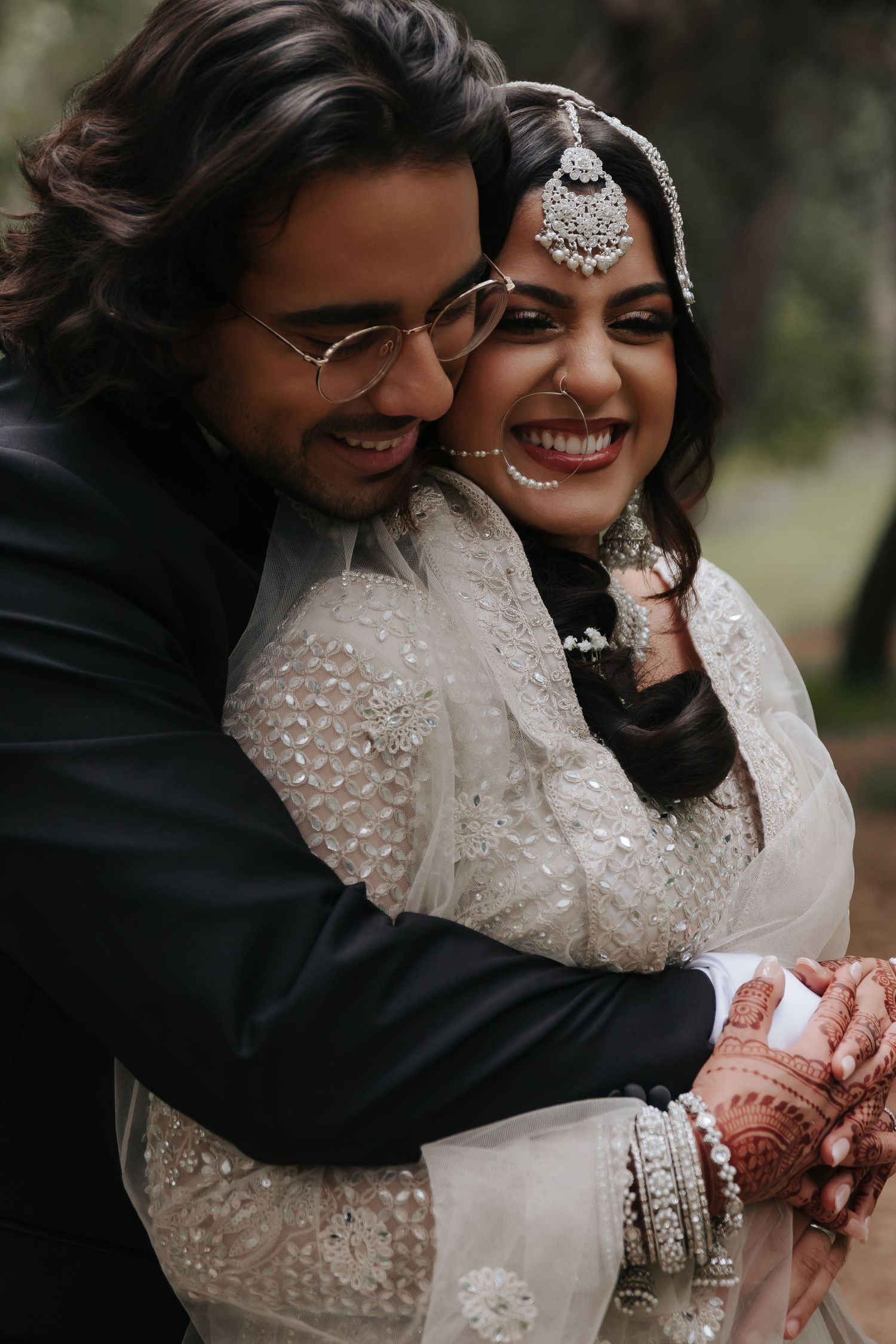 A joyful close-up of newlyweds embracing, with the bride in traditional South Asian wedding attire.