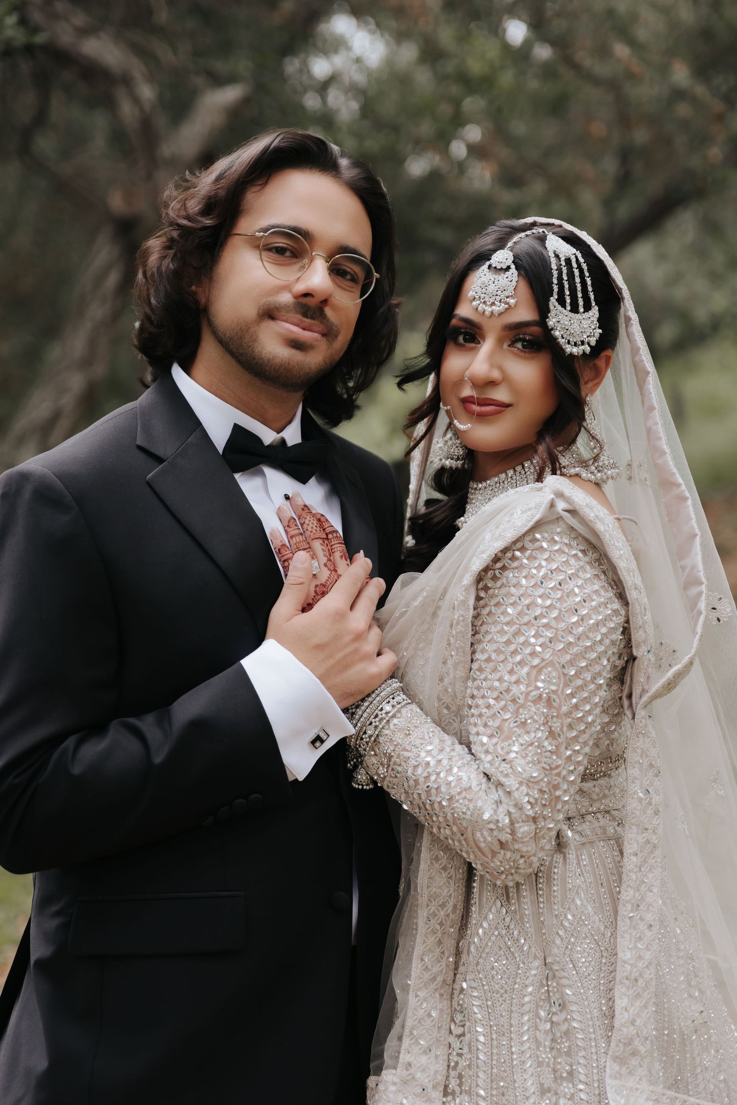 Elegant wedding couple in formal attire posing romantically against a natural backdrop.
