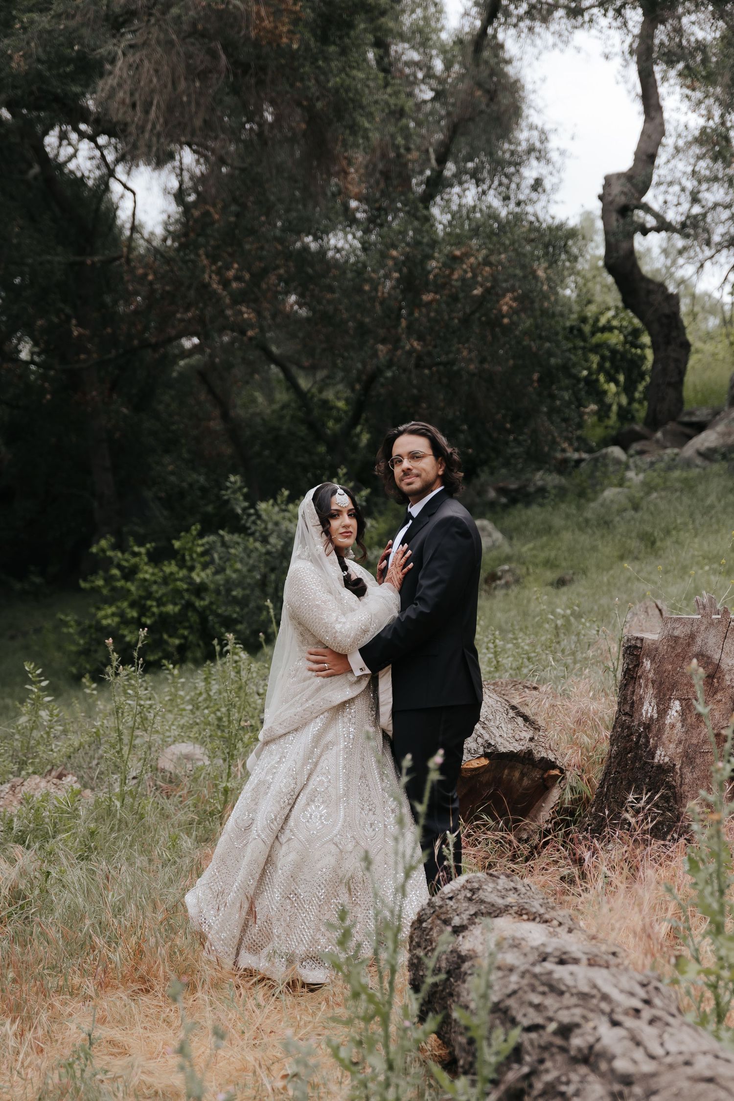 Wedding couple shares intimate moments while posing in a rustic outdoor setting.