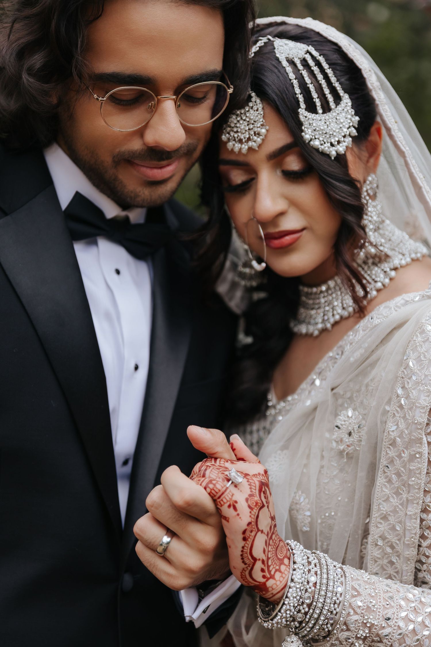 Intimate wedding portraits showing detailed bridal jewelry and traditional South Asian wedding attire in natural setting.
