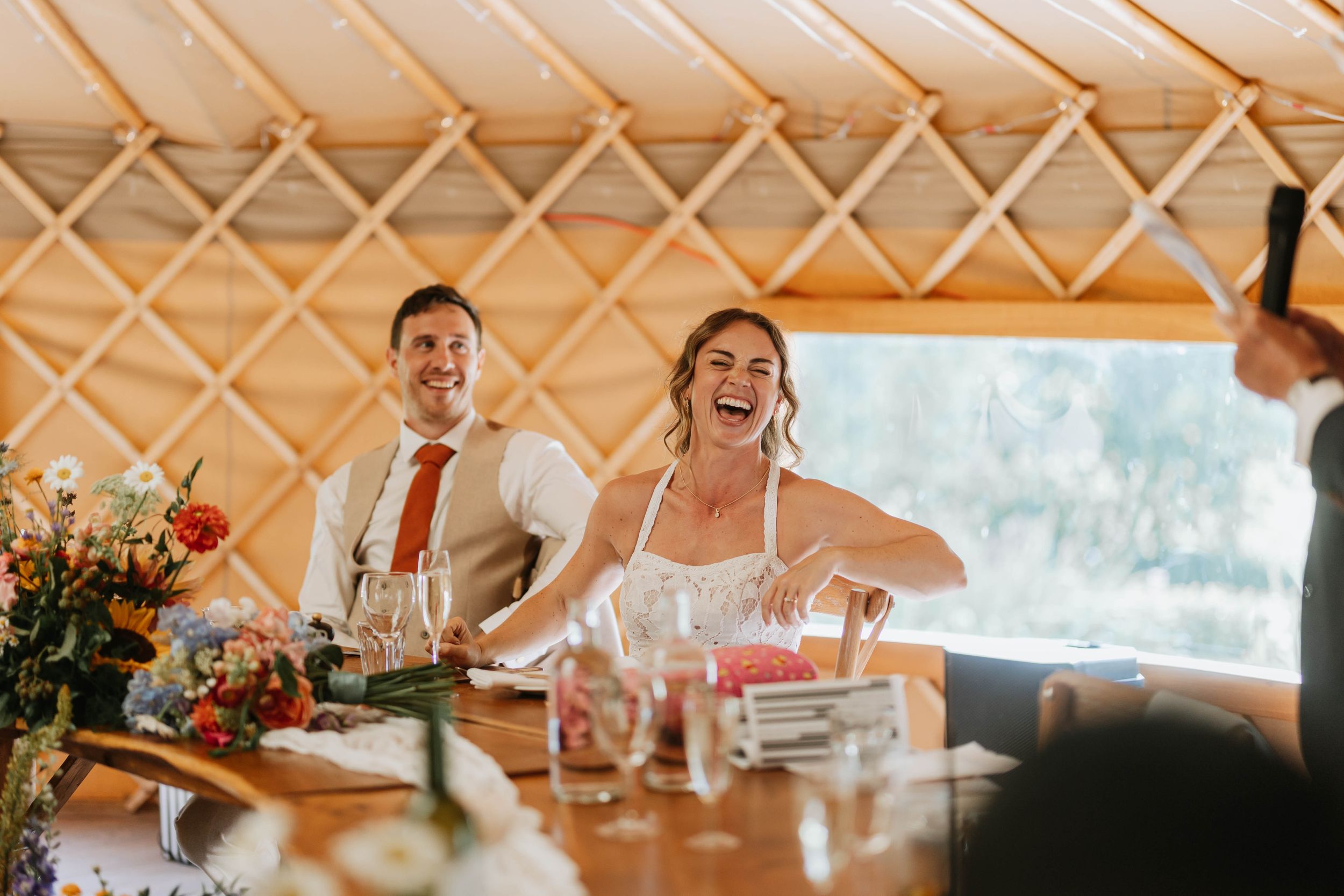 A joyful celebration inside a rustic yurt venue with table settings and floral arrangements at a wedding reception. shropshire wedding photo