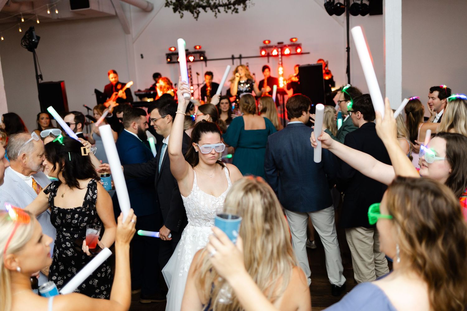 A bride and groom pour champagne together into a tower of glasses at their wedding reception.