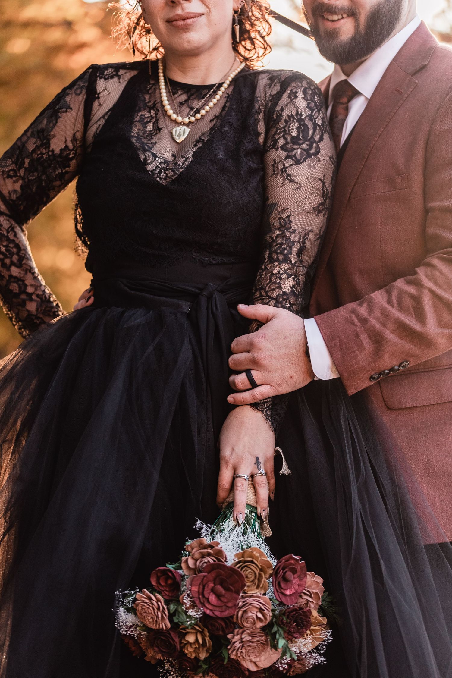Flat lay wedding detail photo featuring elegant black and gold invitation suite, green velvet ring box with wedding bands