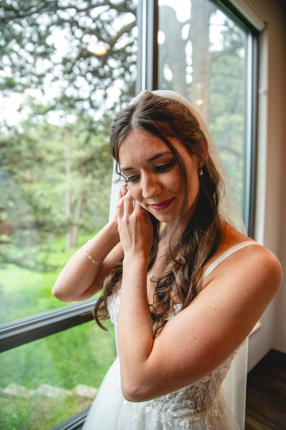 A person in a white wedding dress stands by a window with an emotional expression.