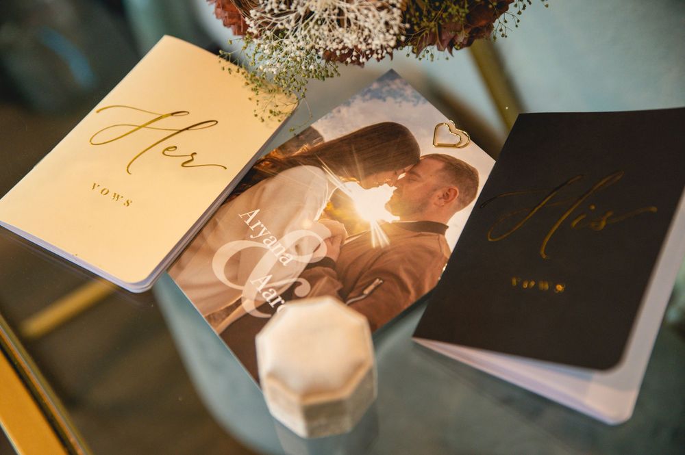 Wedding stationery including black and gold invitation cards displayed alongside a photograph and a candle.