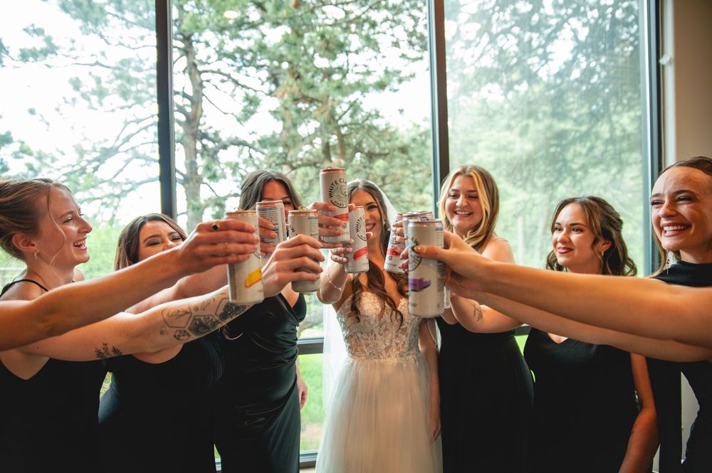 Wedding party in black and white attire toasts with champagne glasses during celebration.