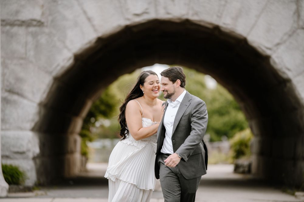 Elegant couple shares an intimate moment under a dramatic stone archway during their wedding.