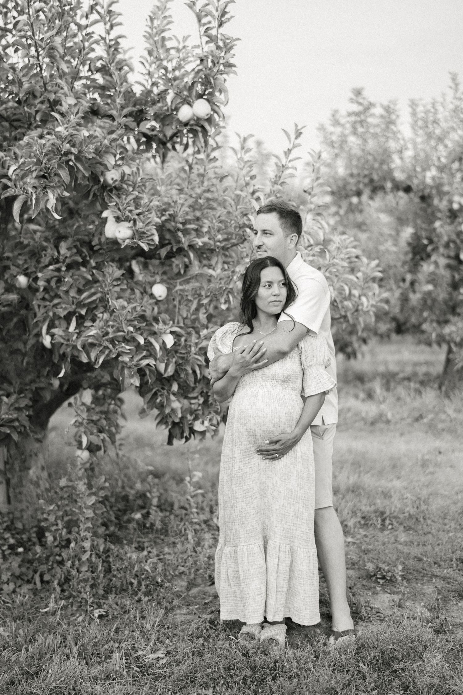 A black and white photo of a romantic moment between a couple in an orchard.