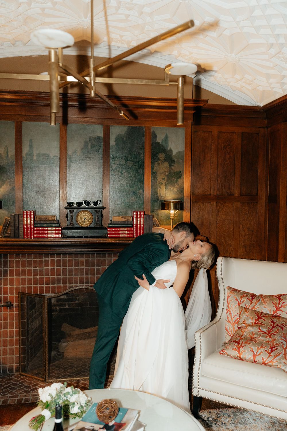 A tender embrace between newlyweds in an elegant room with dark wood paneling and vintage furnishings.