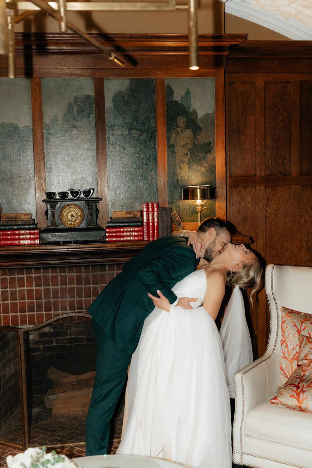 A romantic moment between newlyweds in formal attire inside a wood-paneled room with vintage decor and furniture.