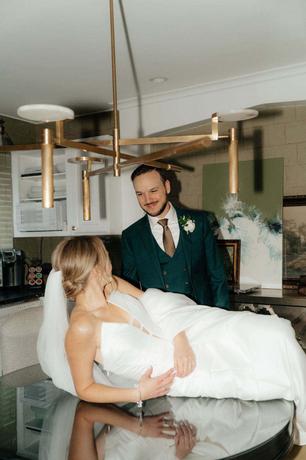 Romantic moment captured during a wedding photoshoot with modern brass chandelier decor.