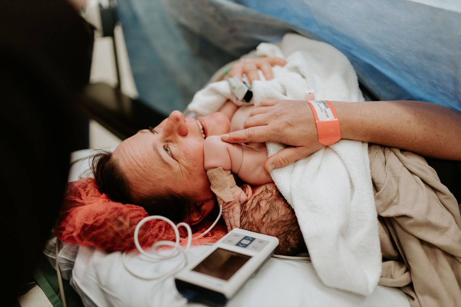 Person lies on medical bed wrapped in blankets while connected to monitoring devices during a hospital procedure.