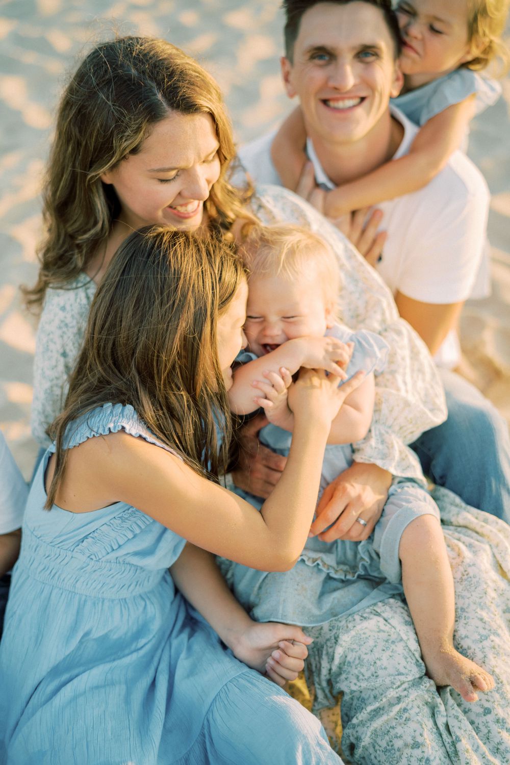 Loving family sharing tender moments together on beach during sunset photo session.