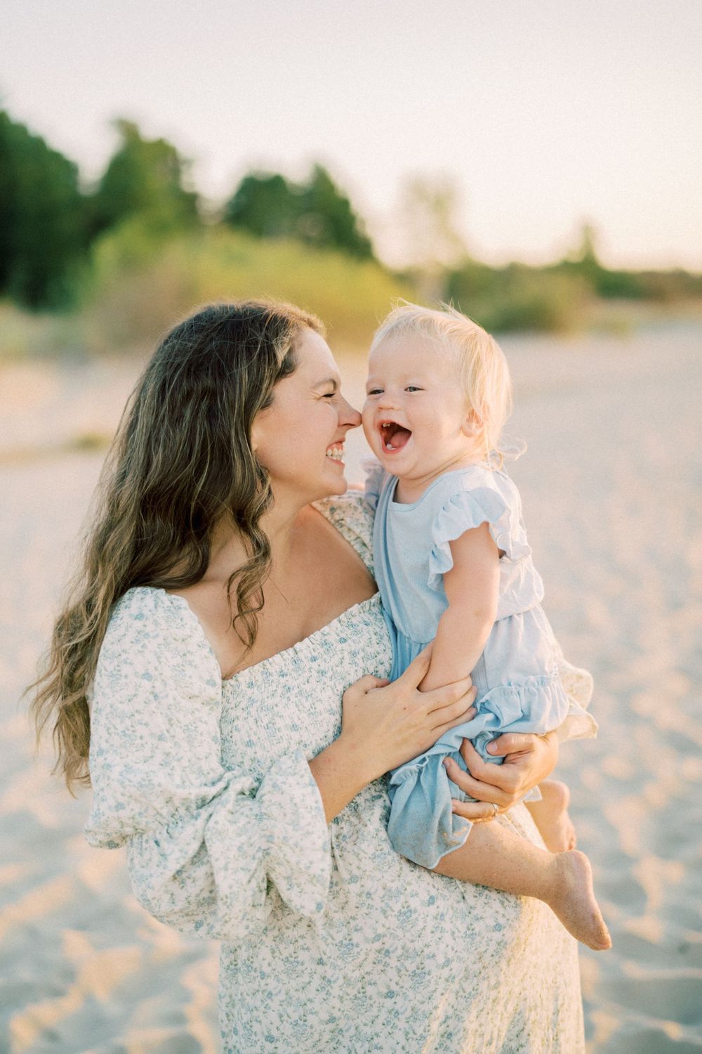 Happy moment between parent and baby on sunny beach with joyful expressions.