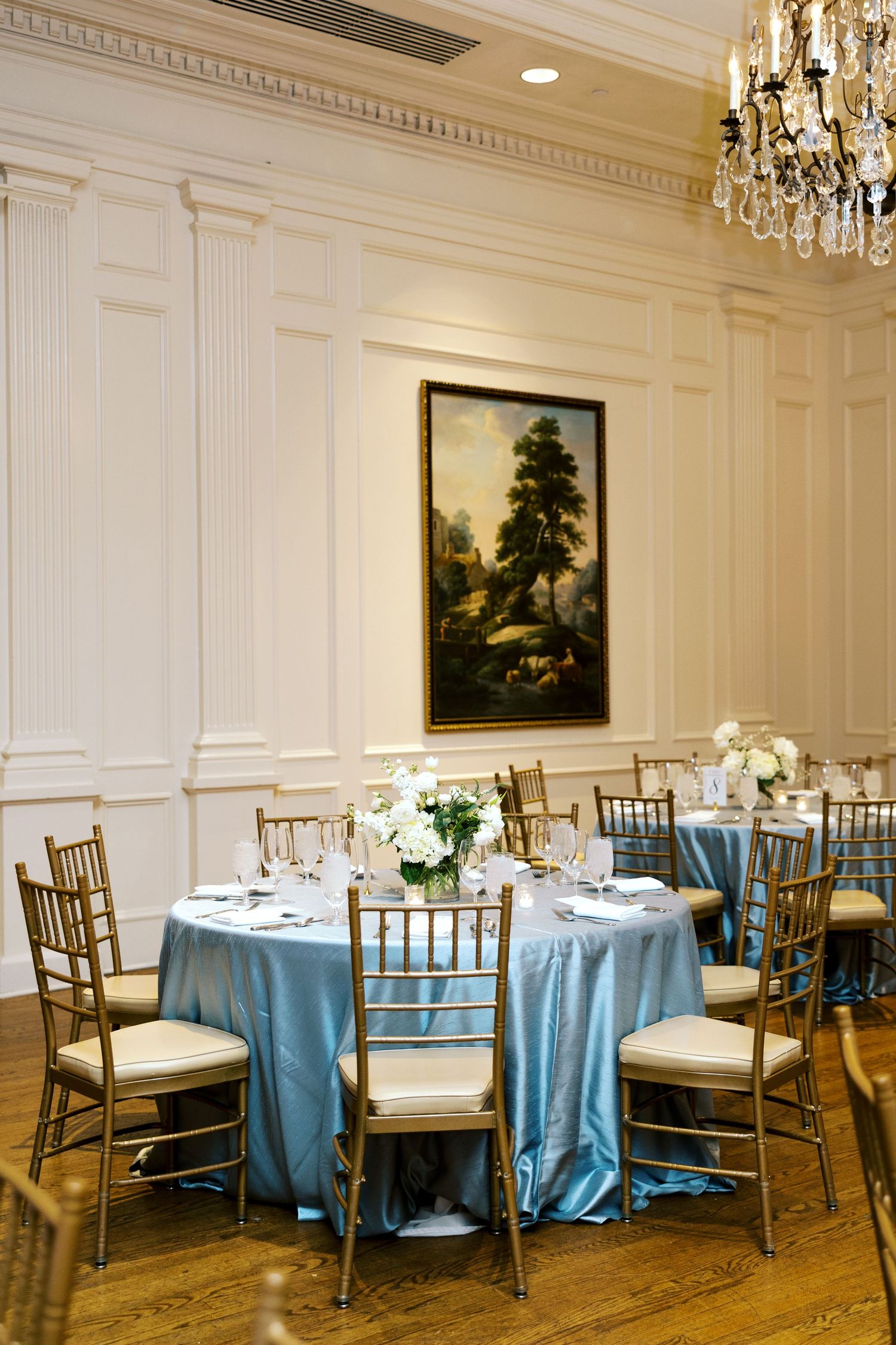 Elegant reception room with crystal chandelier and round tables set with blue linens. NC WEDDING PHOTOGRAPHER, LUXURY WEDDING PHOTOGRAPHER