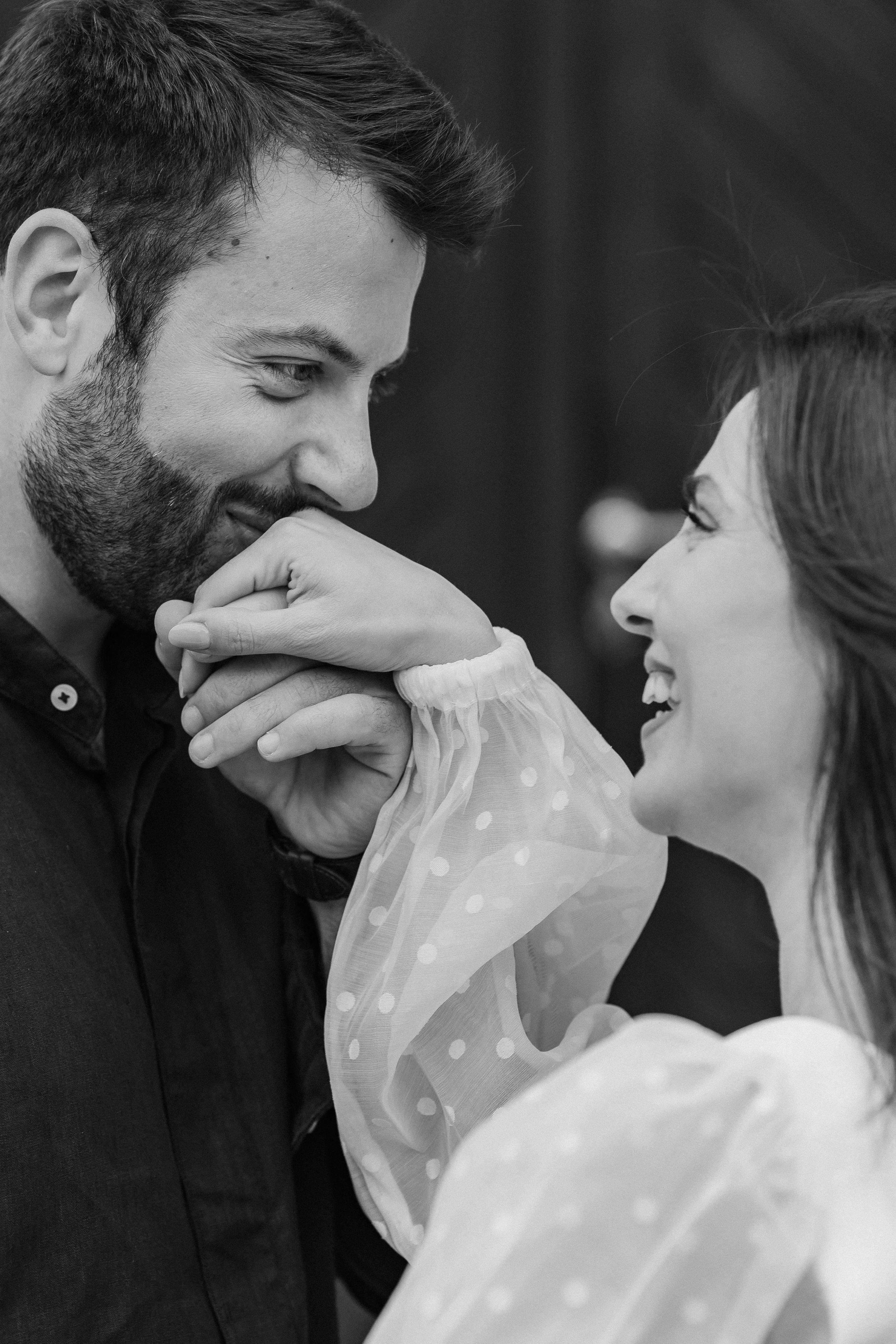 A romantic black and white portrait of a couple sharing a joyful laugh and intimate moment together.